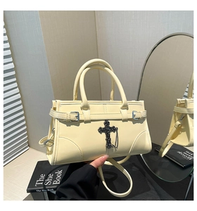 Cream leather handbag with top handles, black gothic cross charm on black books