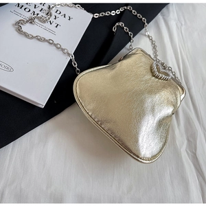 Close-up of golden evening clutch with heart pearl clasp and elegant silver chain
