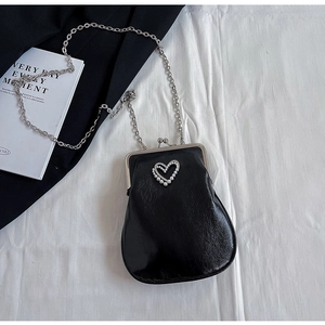 Detail of black mini crossbody bag with vintage silver clasp and heart pearl accent