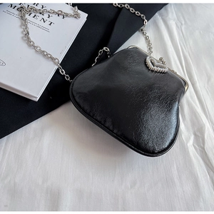 Detail of black faux leather clutch with silver chain and pearl heart-shaped clasp