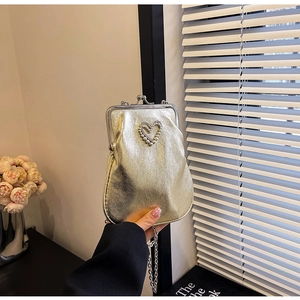 Detailed view of golden metal frame handbag with heart-shaped pearl and rhinestone buckle