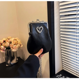 Detail of black kiss lock handbag featuring a heart pearl and rhinestone centerpiece