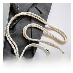 Détail d'un sac à bandoulière blanc avec sangle en corde tissée et ferrures dorées