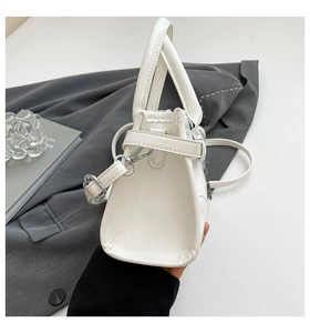 Detail view of white glossy Boston bag with silver hardware and detachable strap