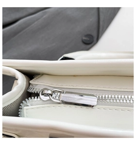 Close-up of the smooth silver metal zipper and white leather texture on Boston bag