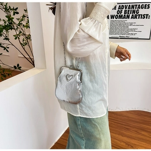 Detail of silver chain crossbody bag featuring heart-shaped bead decor and leather texture