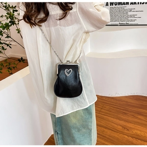 Close-up of black PU crossbody bag featuring a silver chain and vintage heart-shaped clasp