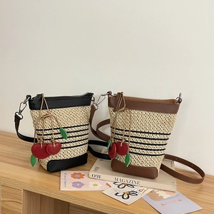 Handwoven raffia crossbody bag with leather trim and decorative red cherry pendants