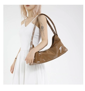 Close-up of brown patent leather hobo bag with silver metallic rivets on shoulder strap