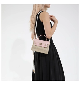 Détail du sac boîte en paille avec rabat rose et bandoulière en corde sur robe noire