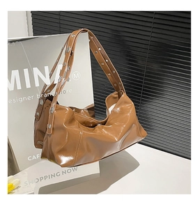 Detail of brown glossy crescent bag with silver stud decorations on a wide strap