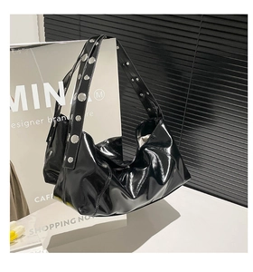 Close-up of black glossy patent leather shoulder bag with silver rivet stud details