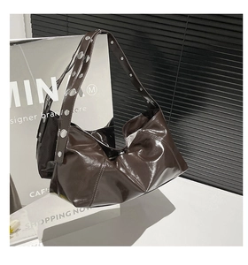 Detail of dark brown glossy patent leather shoulder bag with silver metal studs and rivets