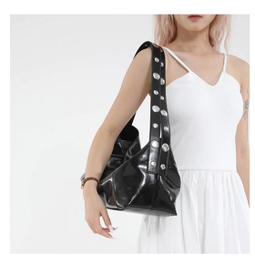 Detail of black patent leather shoulder bag with silver metallic studs on the strap