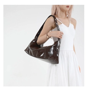 Detail view of deep brown glossy leather hobo bag with metallic rivet shoulder strap