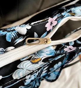 Detail of smooth metal zipper and blue floral print on black tote shopping bag