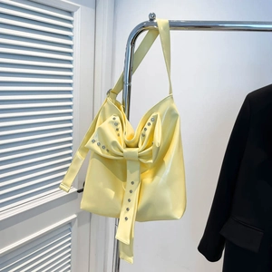 Detail shot of pale yellow PU tote bag showing rhinestones on a large bow decoration