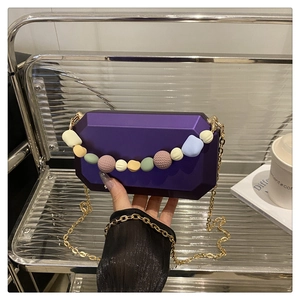 Detail of purple acrylic box bag with colorful macaron beads and gold chain strap