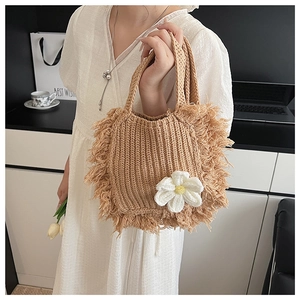 Detail of camel crochet handbag featuring handmade white flower and fringe tassels