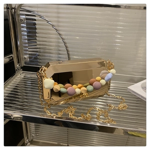 Detail of a gold box clutch featuring macaron colored beads and a chunky metal chain strap