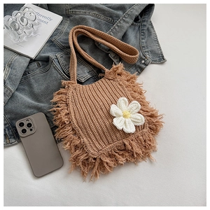 Detail of handmade knit crossbody bag with boho fringe and daisy floral accent
