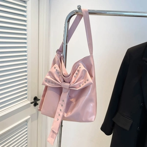 Close-up of pink patent leather tote bag featuring a large bow and silver studs