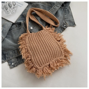 Detail of hand-woven crossbody bag featuring bohemian fringes on blue denim backdrop