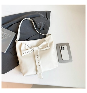 Detail of cream white bucket bag with large bow and silver metallic stud accents