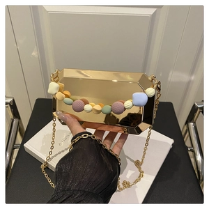 Macro shot of gold octagonal evening bag with colorful textured beads and metallic chain