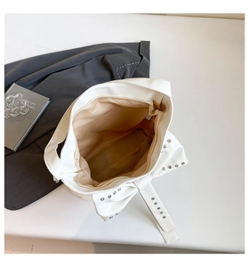 Top view of white tote bag showing spacious interior with silver studs and bow detail