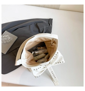 Macro view of white tote interior with rivet bow design and spacious storage space