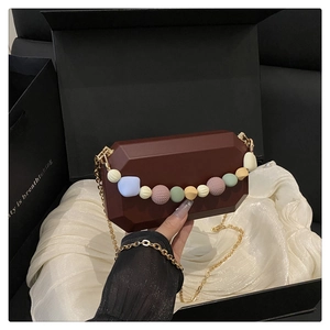 Macro detail of burgundy octagonal evening bag with colorful beads and gold chain