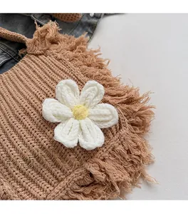 Close-up of woven straw bag with white crochet flower and fringe details in boho style