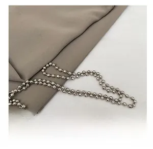 Détail de la bandoulière en chaîne à billes argentées sur un sac en tricot design
