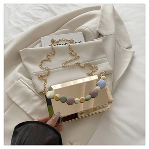 Detail of octagonal gold metal evening bag featuring colorful frosted beaded handle