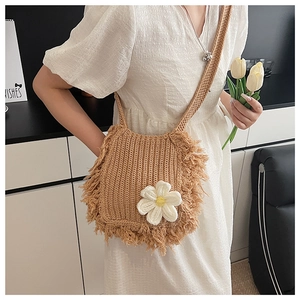 Close-up of khaki handmade crochet crossbody bag with tassels and white flower decoration