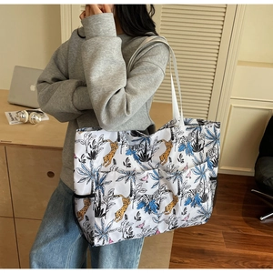 Detalle del bolso tote con estampado de jungla, bolsillos frontales y compartimento lateral