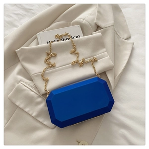 Detail of royal blue octagonal acrylic clutch bag with elegant gold chain strap