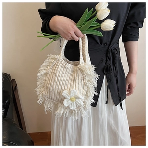 Detail of cream crochet crossbody bag featuring long fringes and a 3D knit flower accent