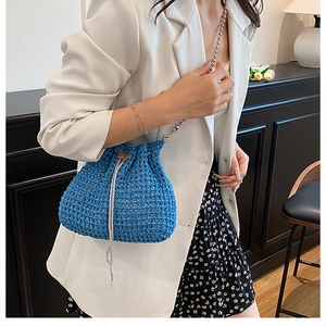 Détail du sac seau bleu en crochet évidé avec fermoir papillon et bandoulière chaîne