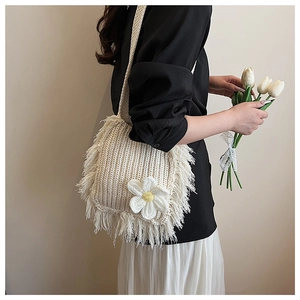 Close-up of cream crochet crossbody bag featuring a large 3D white flower and fringe