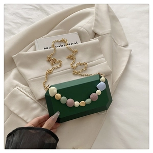 Detail of dark green hexagonal evening clutch with pastel beads and gold chain
