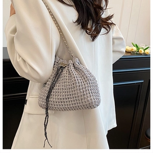 Détail du sac seau au crochet gris avec boucle papillon argentée et bandoulière chaîne