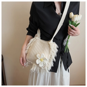 Detail of white crochet shoulder bag with bohemian fringe and yellow daisy flower