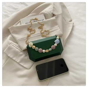 Detail of dark green acrylic box clutch with colorful beads and golden chain strap