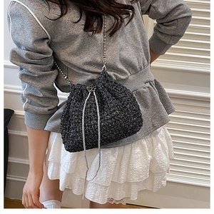 Détails de la texture du sac seau en maille noire avec bandoulière chaîne sur un modèle