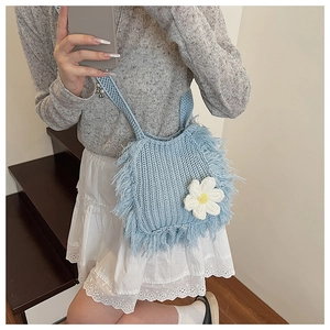 Detail of light blue crochet bag with fringe trim and white 3D daisy flower accent