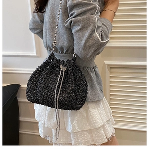 Détail d'un sac seau en tricot noir avec breloque papillon et bandoulière en perles
