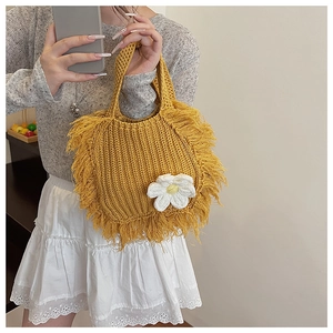 Detail of yellow handmade crochet crossbody bag featuring fringe trim and white flower