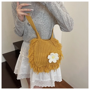 Close-up of ginger yellow crochet crossbody bag featuring long tassels and a white 3D flower